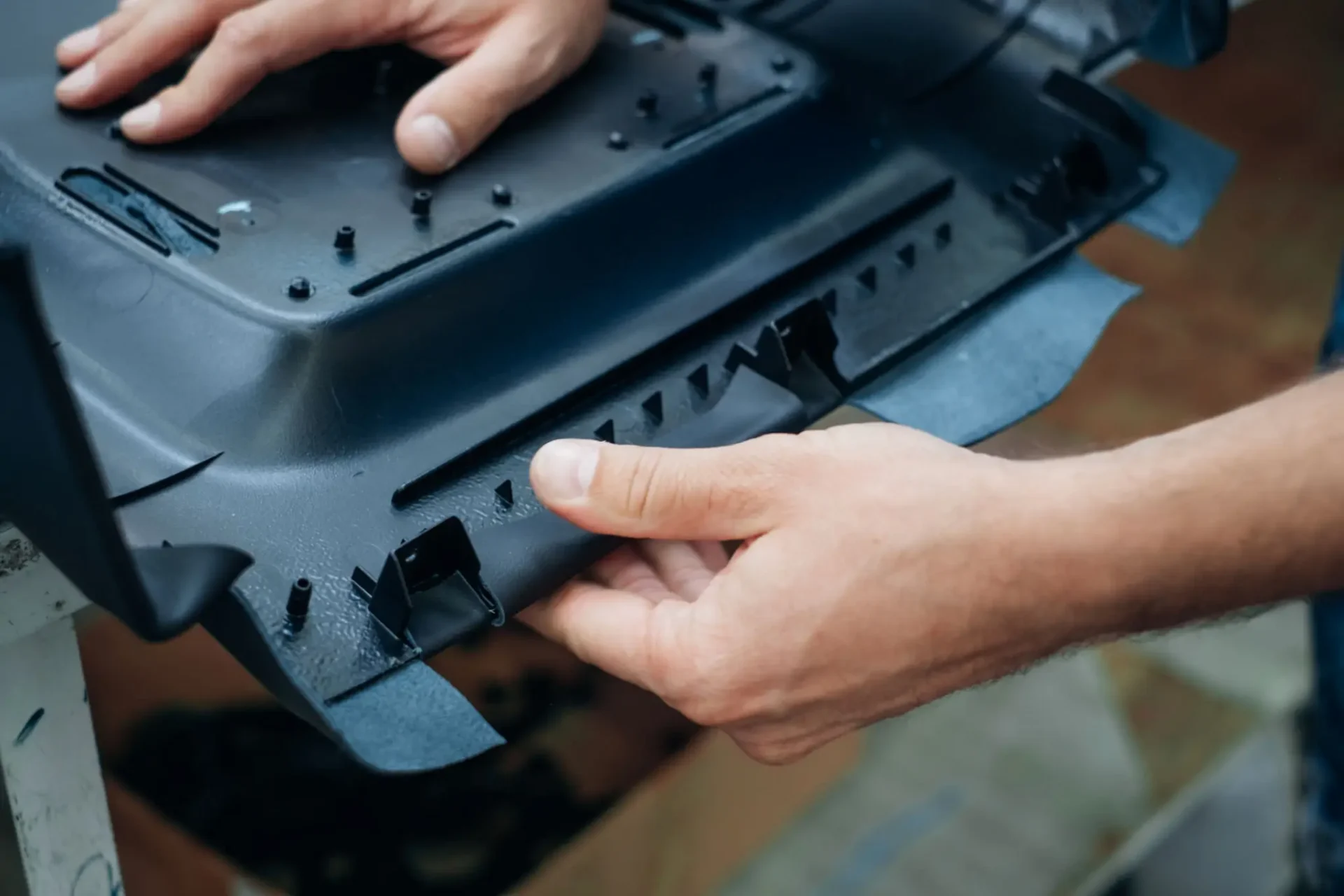 Hands assembling or repairing a black plastic device.